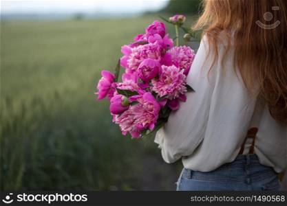 summer - Beautiful girl with a bouquet peony at the field