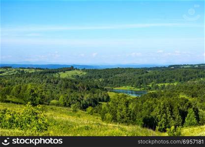 Summer beautiful hills landscape with blue lake. Scenic hillside landscape. Rolling hills and sky. Beautiful landscape.. Summer beautiful hills landscape with blue lake