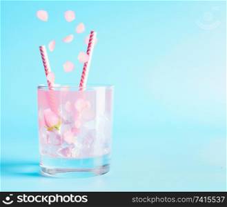 Summer beverage with rose petals and flowers. Refreshment drinks. Iced lemonade or cocktail on blue background