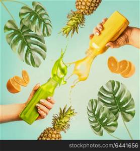 Summer beverages concept. Female hands holding bottles with splash smoothie or juice on blue background with tropical leaves and fruits