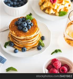 Summer breakfast. Homemade baked ricotta pancakes and Belgian waffles with fresh berries on white wooden table