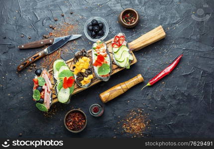 Summer bruschettas or canape with cream cheese,bacon and vegetables.Traditional italian bruschetta. Set of bruschetta on cutting board