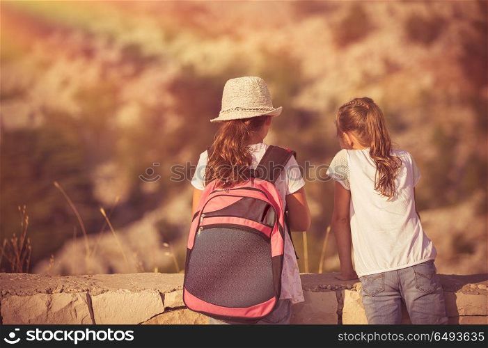 Summer camp adventures, two little girls best friends enjoying mountains hike, schoolchildren on outdoor tour, happy summer holidays in the camp. Kids enjoying hike