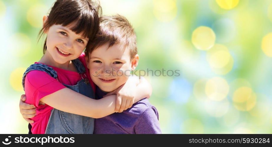 summer, childhood, family, friendship and people concept - two happy kids hugging over green summer lights background