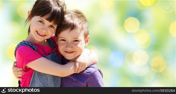 summer, childhood, family, friendship and people concept - two happy kids hugging over green summer lights background