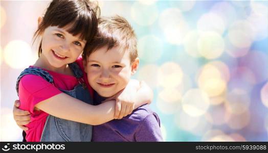 summer, childhood, family, friendship and people concept - two happy kids hugging over blue lights background