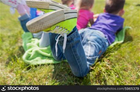 summer, childhood, leisure and people concept - close up of happy kids lying on picnic blanket outdoors