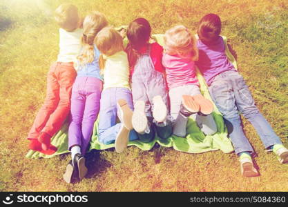 summer, childhood, leisure and people concept - group of happy kids lying on blanket or cover outdoors. group of kids lying on blanket or cover outdoors. group of kids lying on blanket or cover outdoors