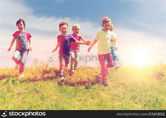 summer, childhood, leisure and people concept - group of happy kids playing tag game and running on green field outdoors. group of happy kids running outdoors