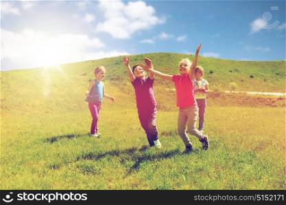 summer, childhood, leisure and people concept - group of happy kids playing tag game and running on green field outdoors. group of happy kids running outdoors