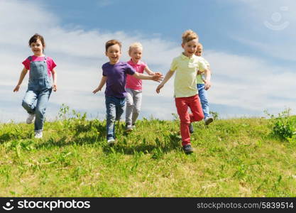 summer, childhood, leisure and people concept - group of happy kids playing tag game and running on green field outdoors