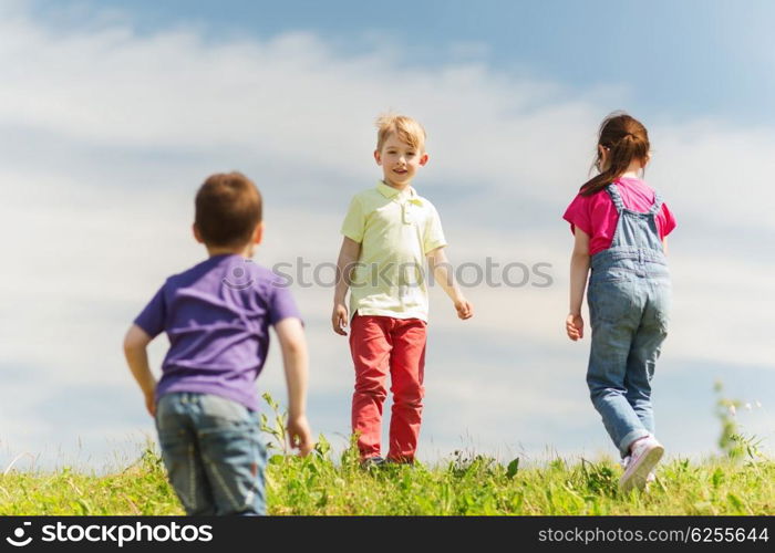 summer, childhood, leisure and people concept - group of happy kids playing game on green field outdoors