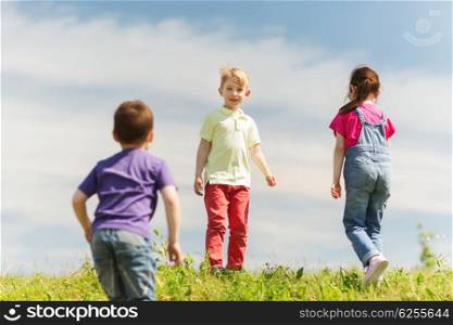 summer, childhood, leisure and people concept - group of happy kids playing game on green field outdoors