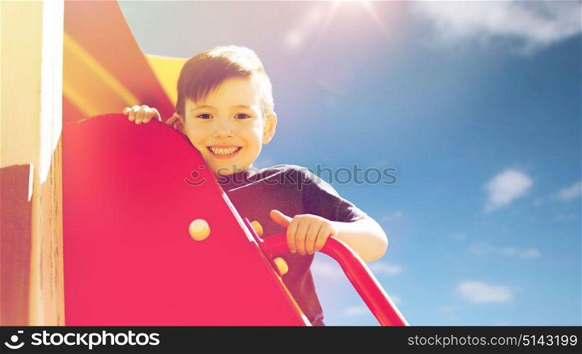 summer, childhood, leisure and people concept - happy little boy on children playground climbing frame. happy little boy climbing on children playground