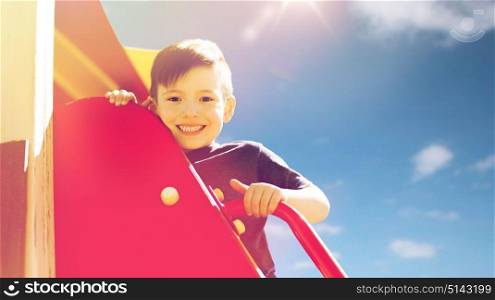 summer, childhood, leisure and people concept - happy little boy on children playground climbing frame. happy little boy climbing on children playground