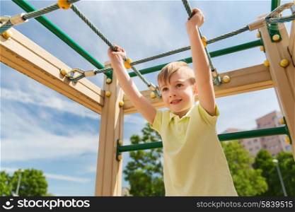 summer, childhood, leisure and people concept - happy little boy on children playground climbing frame