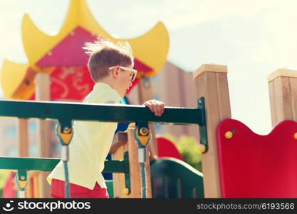 summer, childhood, leisure and people concept - happy little boy on children playground climbing frame