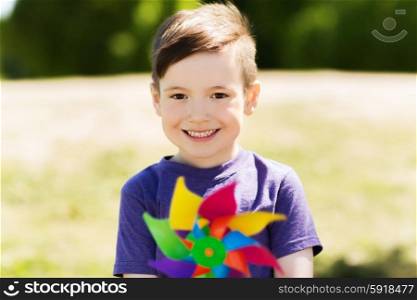 summer, childhood, leisure and people concept - happy little boy with colorful pinwheel toy outdoors