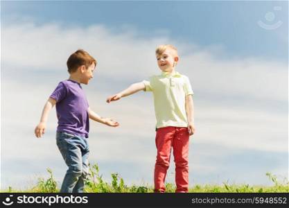 summer, childhood, leisure and people concept - happy little boys outdoors on green field