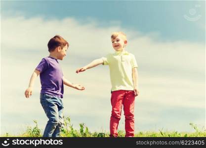 summer, childhood, leisure and people concept - happy little boys outdoors on green field
