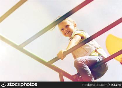 summer, childhood, leisure and people concept - happy little girl on children playground climbing frame. happy little girl climbing on children playground