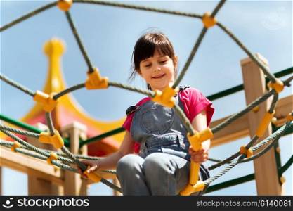 summer, childhood, leisure and people concept - happy little girl on children playground climbing frame