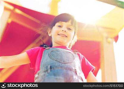summer, childhood, leisure and people concept - happy little girl on playground climbing frame. happy little girl on children playground