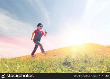 summer, childhood, leisure and people concept - happy little girl running on green summer field. happy little girl running on green summer field