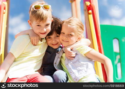 summer, childhood, leisure, friendship and people concept - group of happy kids hugging on children playground