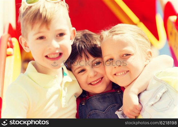 summer, childhood, leisure, friendship and people concept - group of happy kids hugging on children playground