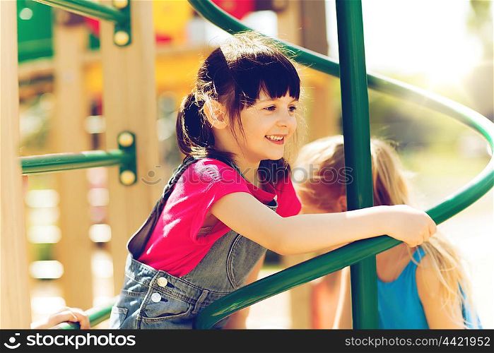 summer, childhood, leisure, friendship and people concept - group of happy little girls on children playground climbing frame