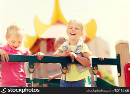 summer, childhood, leisure, friendship and people concept - happy little girls laughing on children playground climbing frame