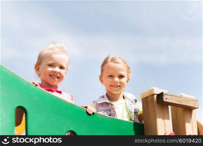 summer, childhood, leisure, friendship and people concept - happy little girls on children playground climbing frame