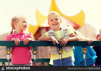 summer, childhood, leisure, friendship and people concept - happy little girls on children playground climbing frame