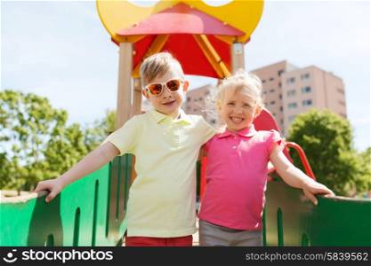 summer, childhood, leisure, friendship and people concept - two happy kids hugging on children playground
