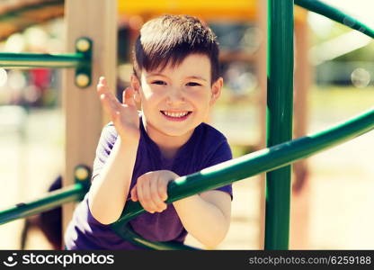 summer, childhood, leisure, gesture and people concept - happy little boy waving hand on children playground climbing frame