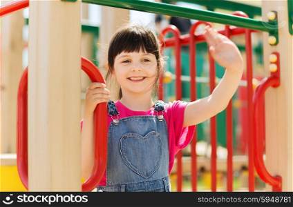 summer, childhood, leisure, gesture and people concept - happy little girl waving hand on children playground climbing frame