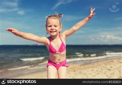summer, childhood, vacation and people concept - happy little girl in swimwear having fun on beach