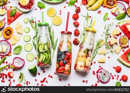 Summer clean and healthy lifestyle and fitness background with various infused water in bottles, colorful sliced ingredients: fruits, berries, vegetables, herbs on white background, top view