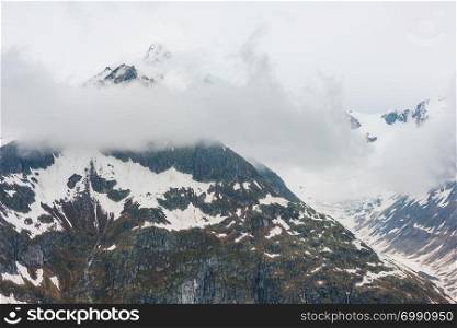 Summer cloudy Alps mountain and Bettmerhorn ridge view from Great Aletsch Glacier and ice fall (Bettmeralp, Switzerland)
