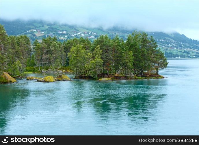 Summer cloudy fjord landscape with fir forest on shore (Norway).