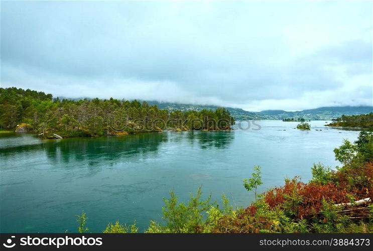 Summer cloudy fjord landscape with fir forest on shore(Norway).