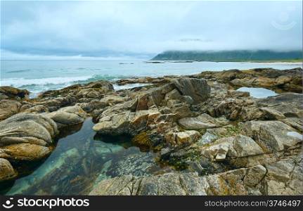 Summer cloudy view of the beach with pool in middle of stones ( Ramberg, Norway, Lofoten).