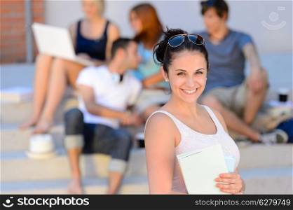Summer college student girl smiling holding books friends in background