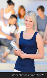 Summer college student girl smiling holding books friends in background