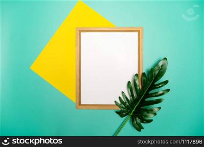 Summer composition. Tropical palm leaves, yellow paper blank, photo frame on pastel green background.