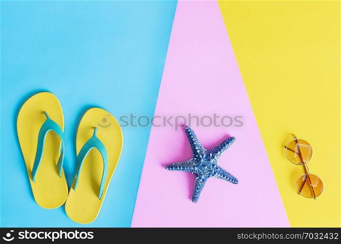 Summer concept. Flat lay of slippers, sunglasses and starfish on colorful background with free space for text.