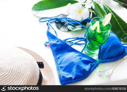 Summer concept iced green color drink, blue stripe bikini and plumeria flower on white background with copy space
