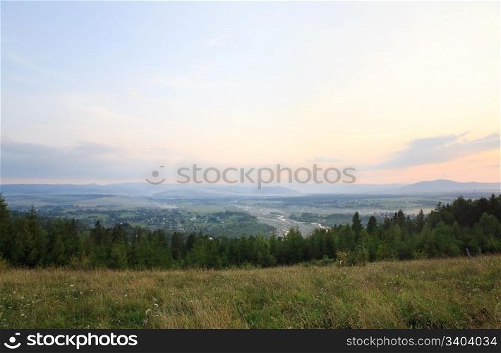 summer countryside foothills landscape with river valley, sunset and mountain behind