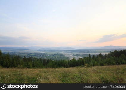 summer countryside foothills landscape with river valley, sunset and mountain behind